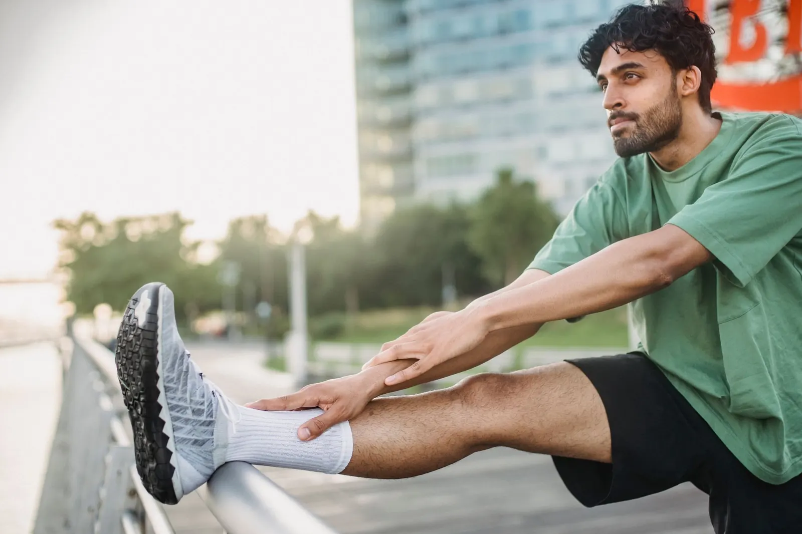 Runner stretching his hamstring on a railing outdoors