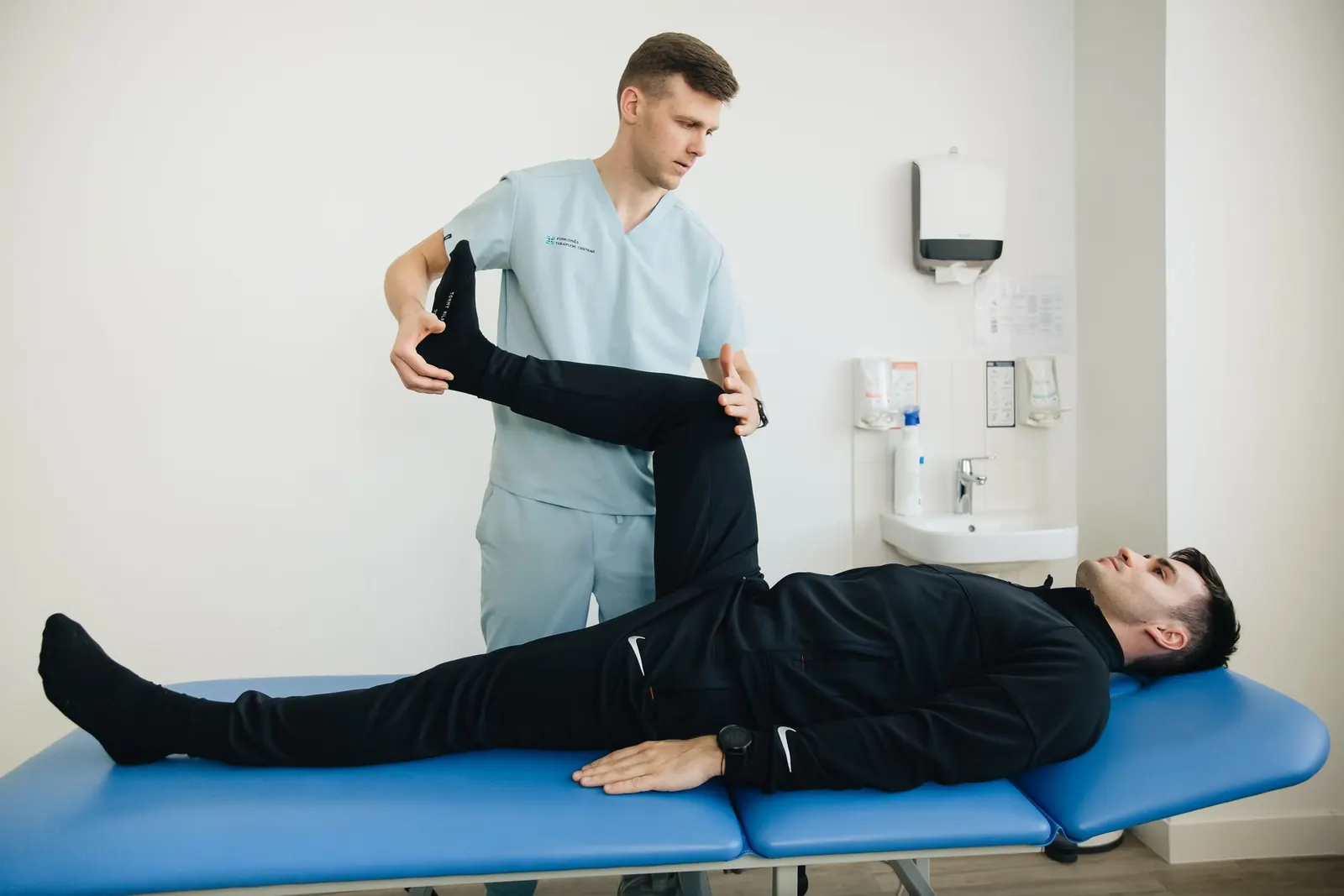 Physiotherapist stretching a patient's leg on a treatment couch
