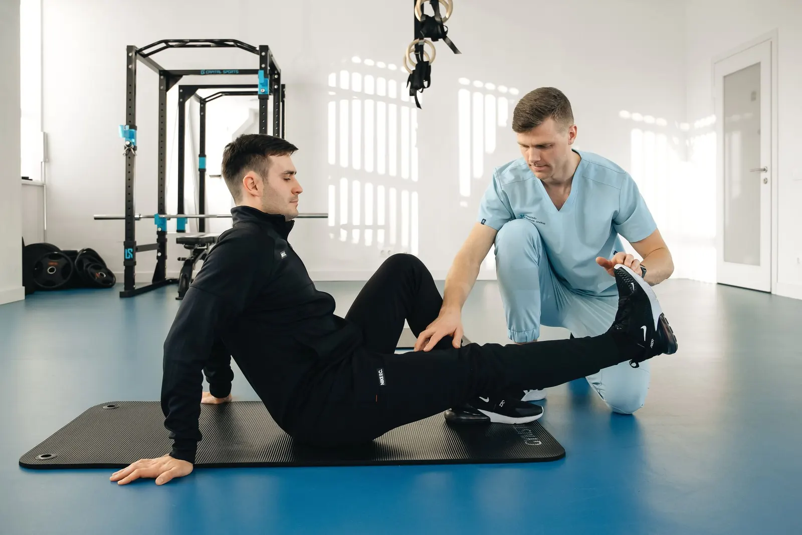 Physiotherapist guiding a leg exercise in a bright rehab gym